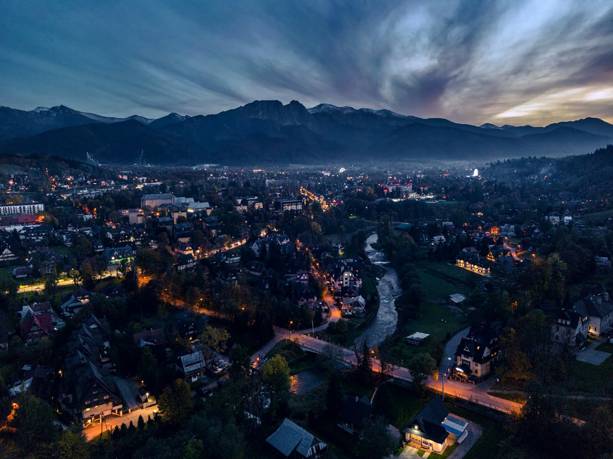 Zakopane o zmierzchu z lotu ptaka, światła ulic i ciemna grań Giewontu na horyzoncie